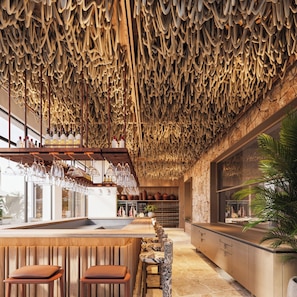 Una zona de bar con techo de madera, taburetes y una estantería para vinos.