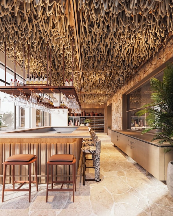A bar area with stools, a counter, and a unique ceiling design. - Hotel Camelot By Artur (Ksamil)