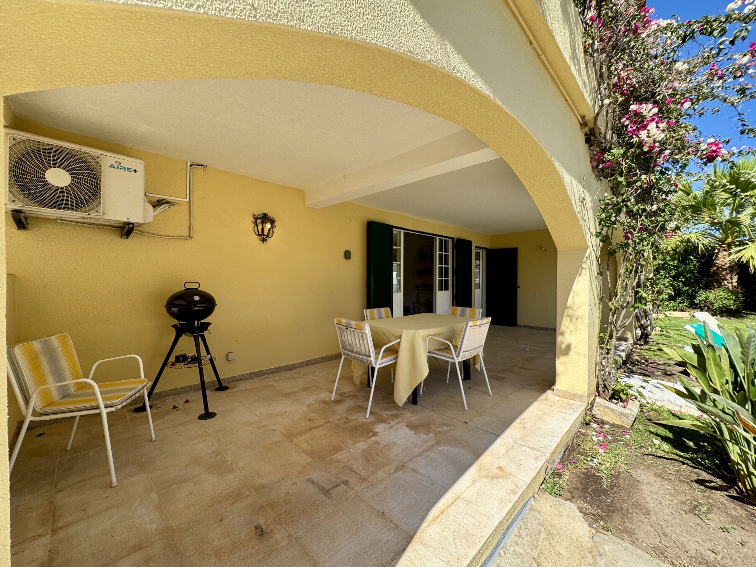 Une terrasse couverte avec une table et des chaises, un barbecue et un ventilateur.