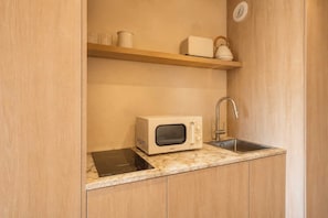 Cuina compacta amb microones, rentapelats i una balda de fusta a la part superior.