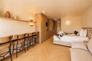 Een hotelkamer met een bed, een zithoek met stoelen, een kledingkast en een douche.