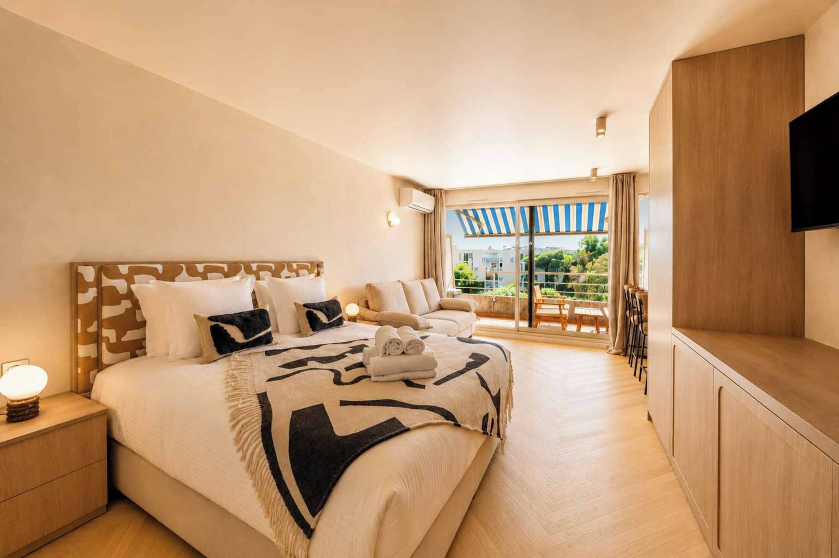 A hotel room with a large bed, a TV, and a balcony with a view.