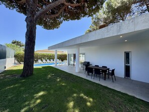 A modern outdoor patio with a pool, a dining area, and a large tree. - ALBUFEIRA BALAIA VILLA 2 WITH POOL by HOMING (Albufeira)