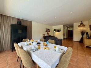 A dining area with a table set for breakfast, a sofa in the background, and a kitchen area. - ALBUFEIRA BALAIA VILLA 2 WITH POOL by HOMING (Albufeira)