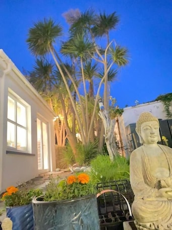 A statue, a house, and palm trees.
