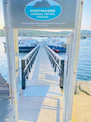 A pier leading to a dock with boats, a sign for Portmagee Seasonal Visitors Pontoon, and contact information for Kilrush Marina.