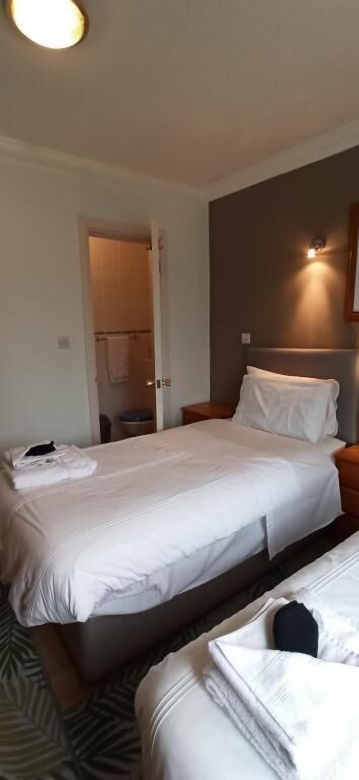 A hotel room with two beds, a bathroom, and a nightstand.