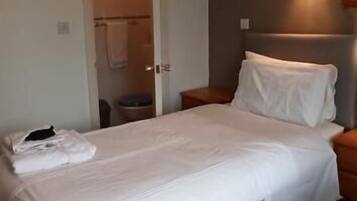 A hotel room with two beds, a bathroom, and a nightstand.