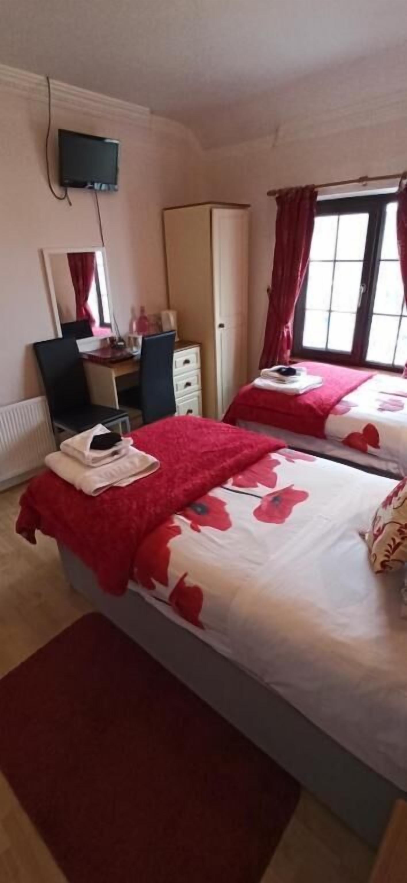 A hotel room with two beds, a desk, a chair, a wardrobe, and a television.