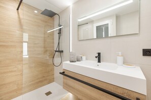 Een moderne badkamer met een douche, een wastafel met spiegel en een handdoekrek.