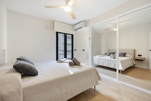 Een moderne slaapkamer met een bed, een plafondventilator en een grote spiegel.