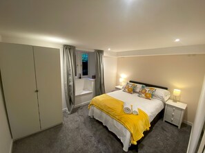 A hotel room with a bed, bedside tables, a wardrobe, and a bathroom visible through a door. - Greyfriars Garden No (14A) | St Andrews (St Andrews)
