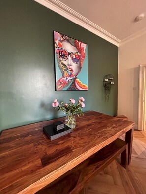 A wooden bench with a vase of pink flowers and a framed artwork on a teal wall. - Greyfriars Garden No (14A) | St Andrews (St Andrews)