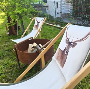 Twee fauteuils, een schilderij van een hert, een metalen emmer met hout en een gazon.