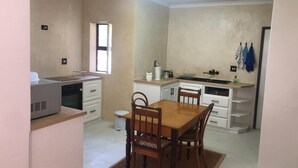 A compact kitchen with a dining table, chairs, a refrigerator, and a window. - Elegant Two-bedroom Apartment on the Banks of the Eerste River in Stellenbosch (Stellenbosch)