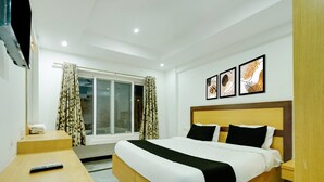 A hotel room with a bed, a TV, a window with curtains, and three framed pictures on the wall. - Classic Room With Twin Bed Hotel Looranova (Tirupati)