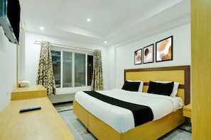 A hotel room with a bed, a TV, a window with curtains, and three framed pictures on the wall. - Classic Room With Twin Bed Hotel Looranova (Tirupati)