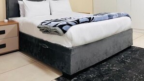Une chambre à coucher avec un lit, une table de chevet, une armoire et un tapis noir.