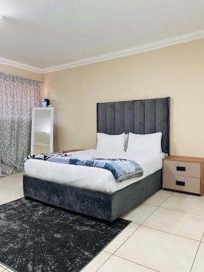 A bedroom with a bed, bedside tables, a nightstand, a dresser, and a rug. - Room-airport Continental Guest House (Kempton Park)