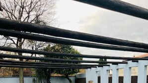 Une piscine dotée d’une terrasse carrelée, entourée d’un mur blanc et agrémentée d’une structure en forme de pergola.