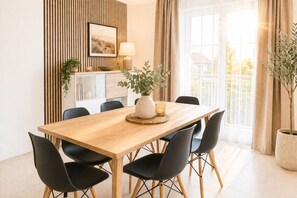 Un comedor moderno con una mesa de madera, sillas negras, un jarrón con plantas verdes y un cuadro en la pared.