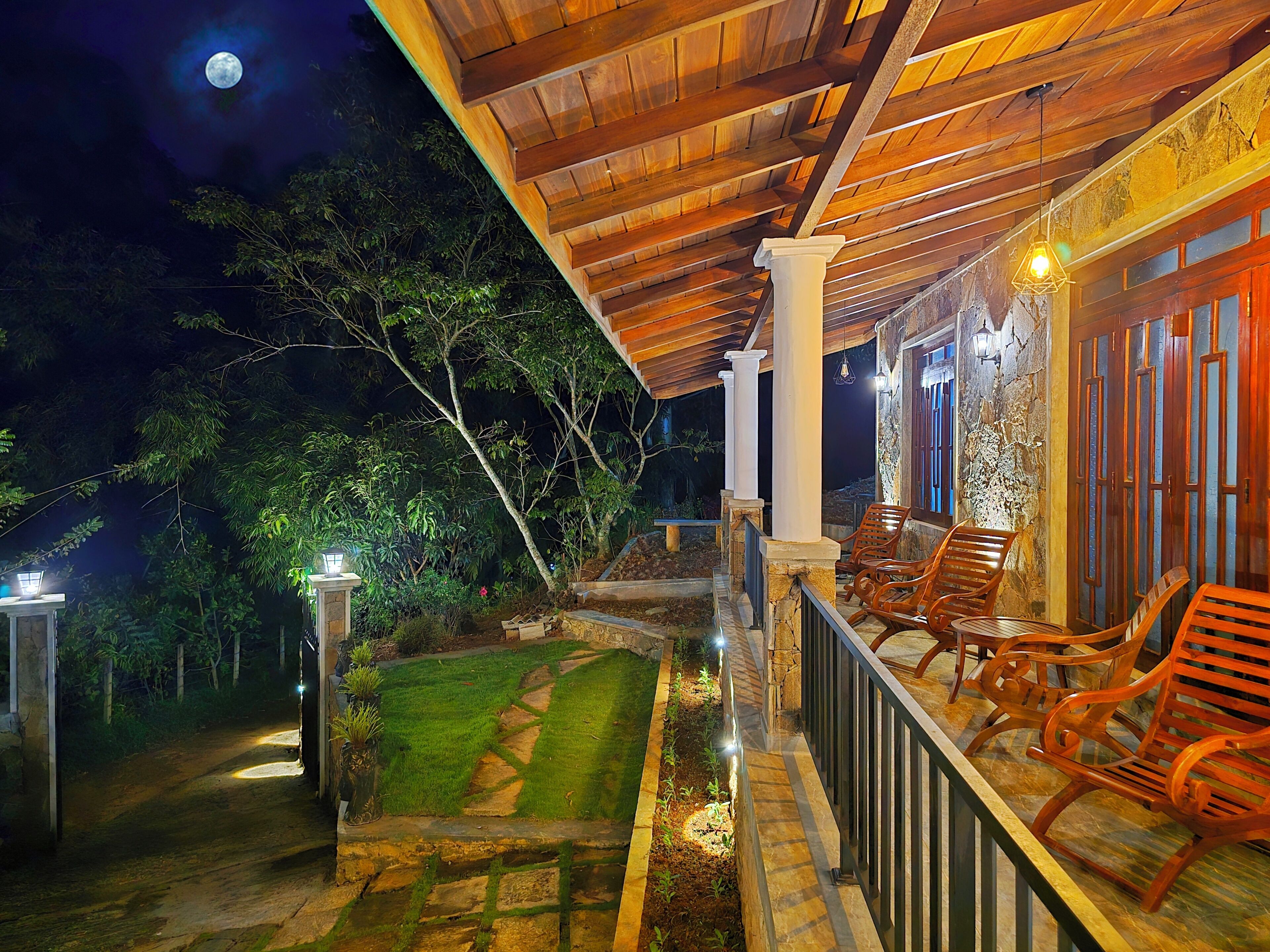 A covered outdoor area with stone steps, wooden chairs, and a pathway leading to a building.