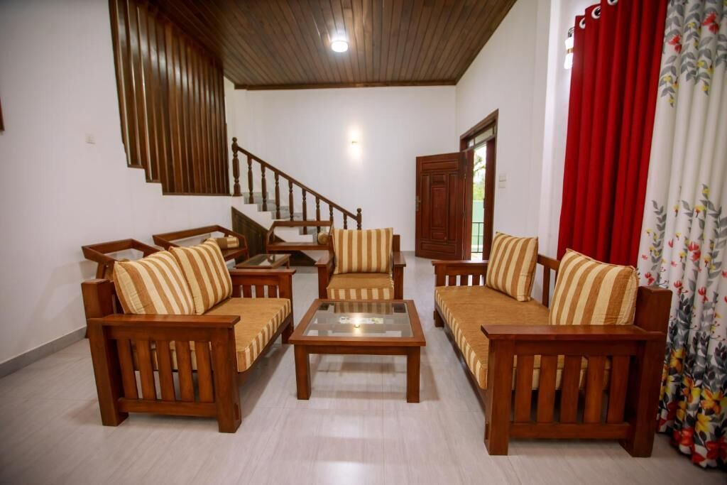 A living room with wooden furniture, a glass coffee table, a staircase, and a door.