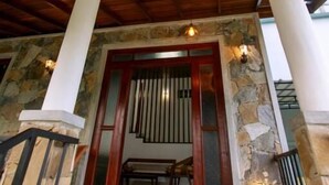 A covered entrance with stone walls, wooden beams, and a bench.