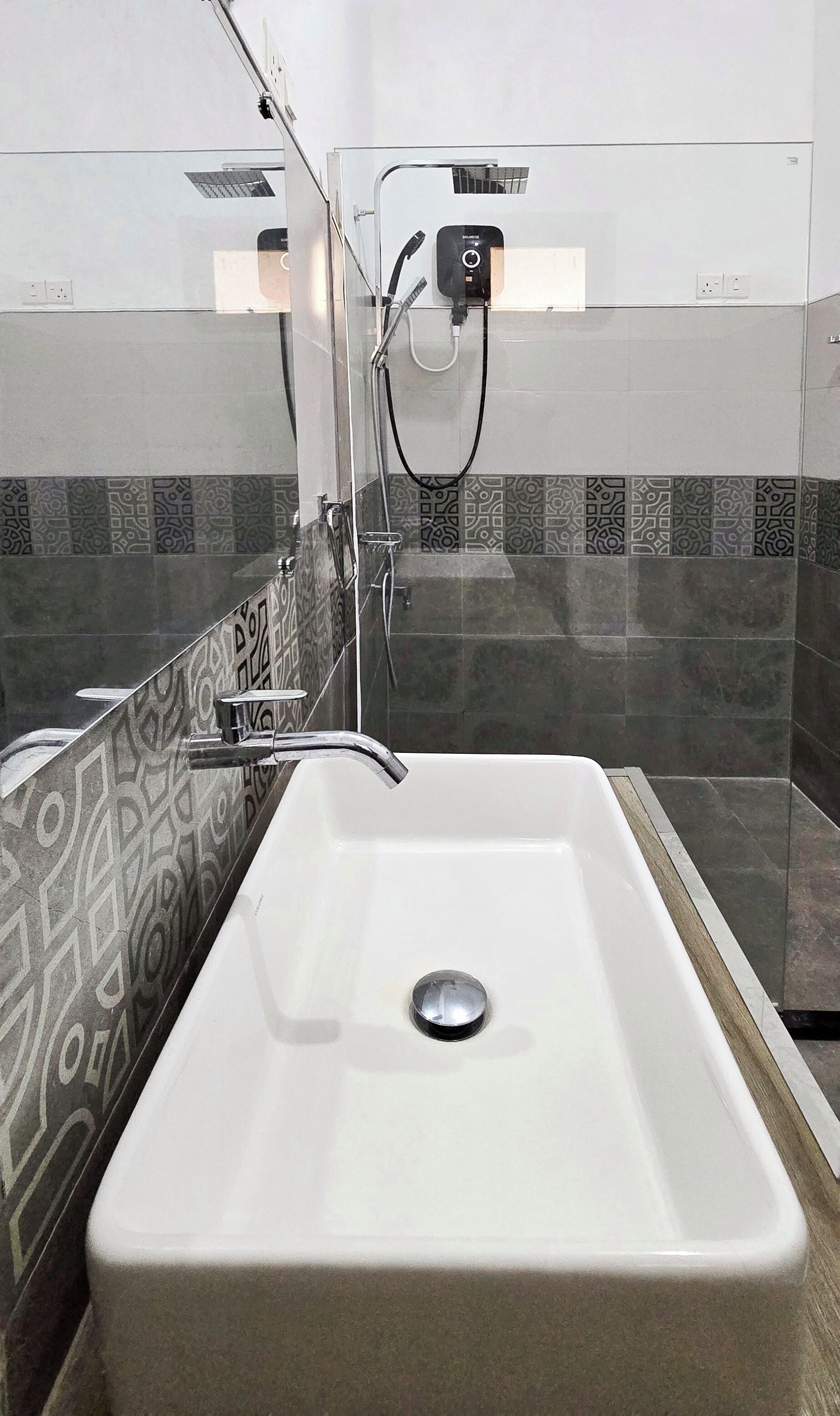 Un bagno con un lavandino bianco, un soffione a mano e piastrelle decorate sulle pareti.