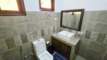 A bathroom with a toilet, sink, mirror, and patterned tiles.