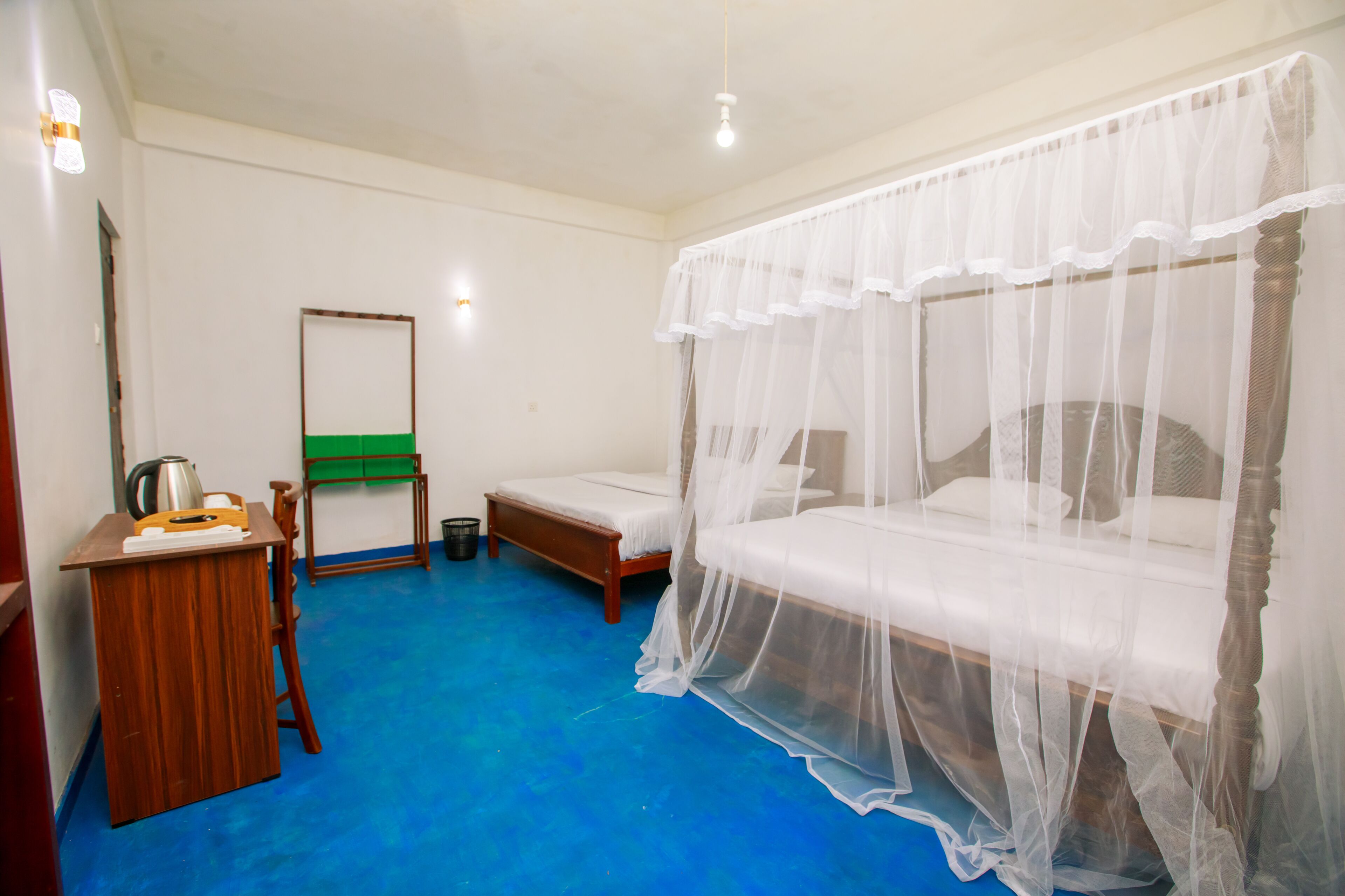 A room with a bed, a desk, a chair, a green mat, and a mirror.