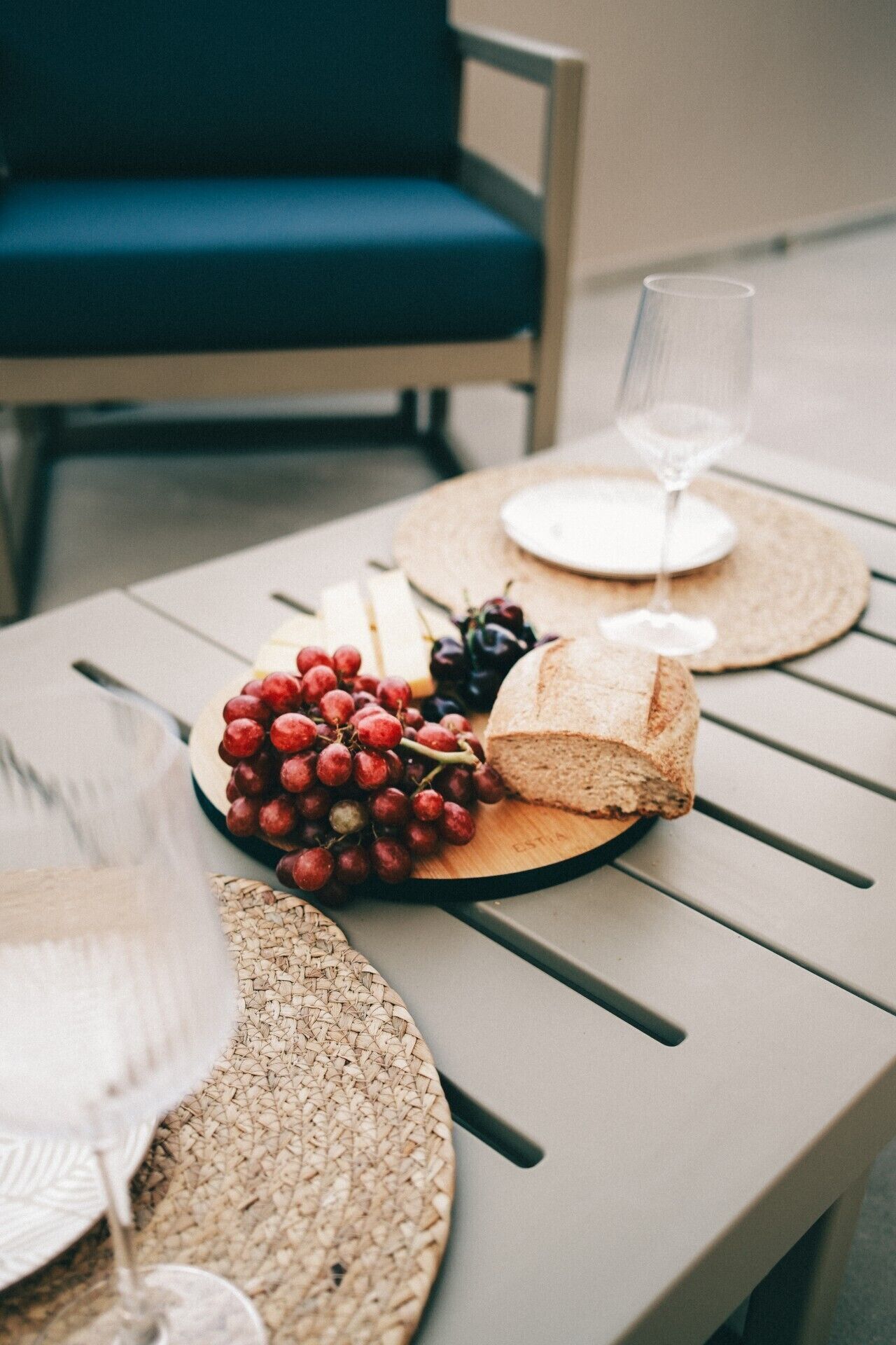 A table with a plate of grapes, a loaf of bread, and a glass of water.