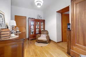 A wooden floor, a wooden chair, a wooden cabinet, a lamp, and a bookshelf. - Chambre Perle – 12 m² (Monclar-de-Quercy)