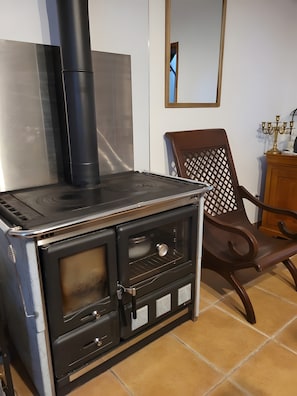 A kitchen with a stove, oven, and a chair.