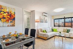 Ein modernes Wohnzimmer mit Essbereich, einer Couch und Blick auf die Stadt.