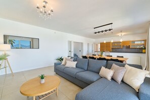 Ein modernes Wohnzimmer mit einem grauen Sofa, einem Holztisch und einer Pendelleuchte.