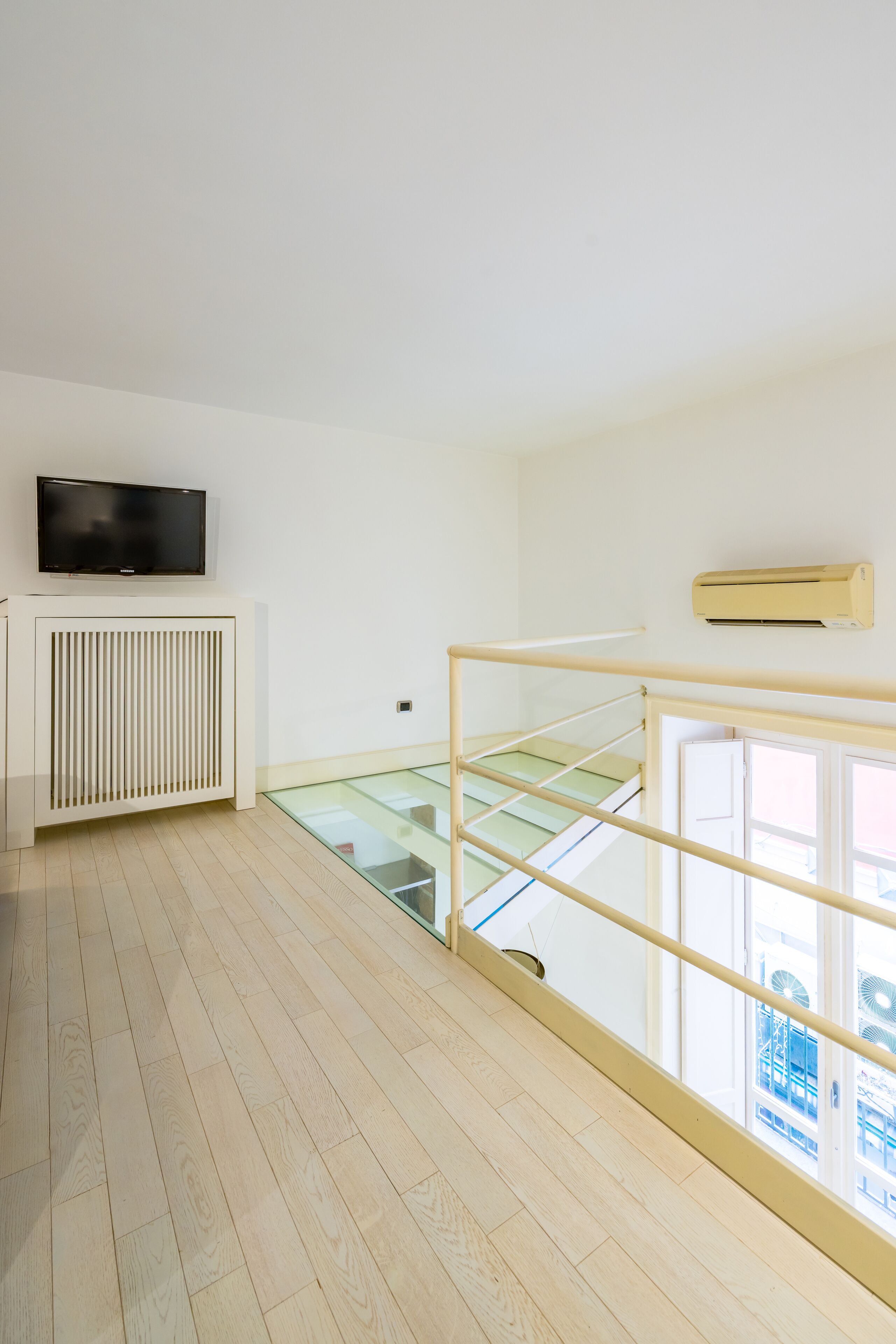 Une chambre moderne dotée d’un téléviseur à écran plat, d’un radiateur blanc et d’un escalier en verre.