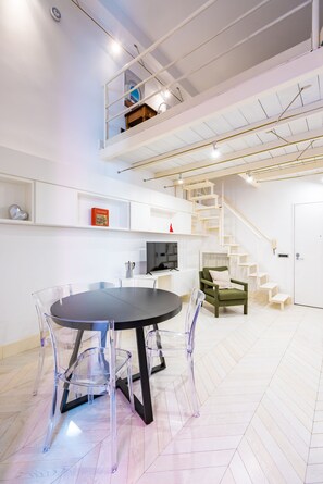 Ein geräumiges Zimmer mit rundem Tisch und Stühlen, einer Treppe und einem grünen Sessel.