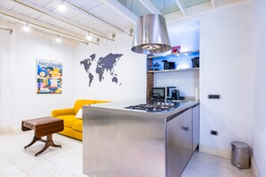 A modern kitchen with a central island, a built-in stove, and a hanging light fixture. - Chiaia Prestige by Napoliapartments (Naples)