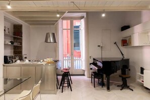 Eine moderne Küche mit Essbereich, einem Klavier und einem großen Fenster.