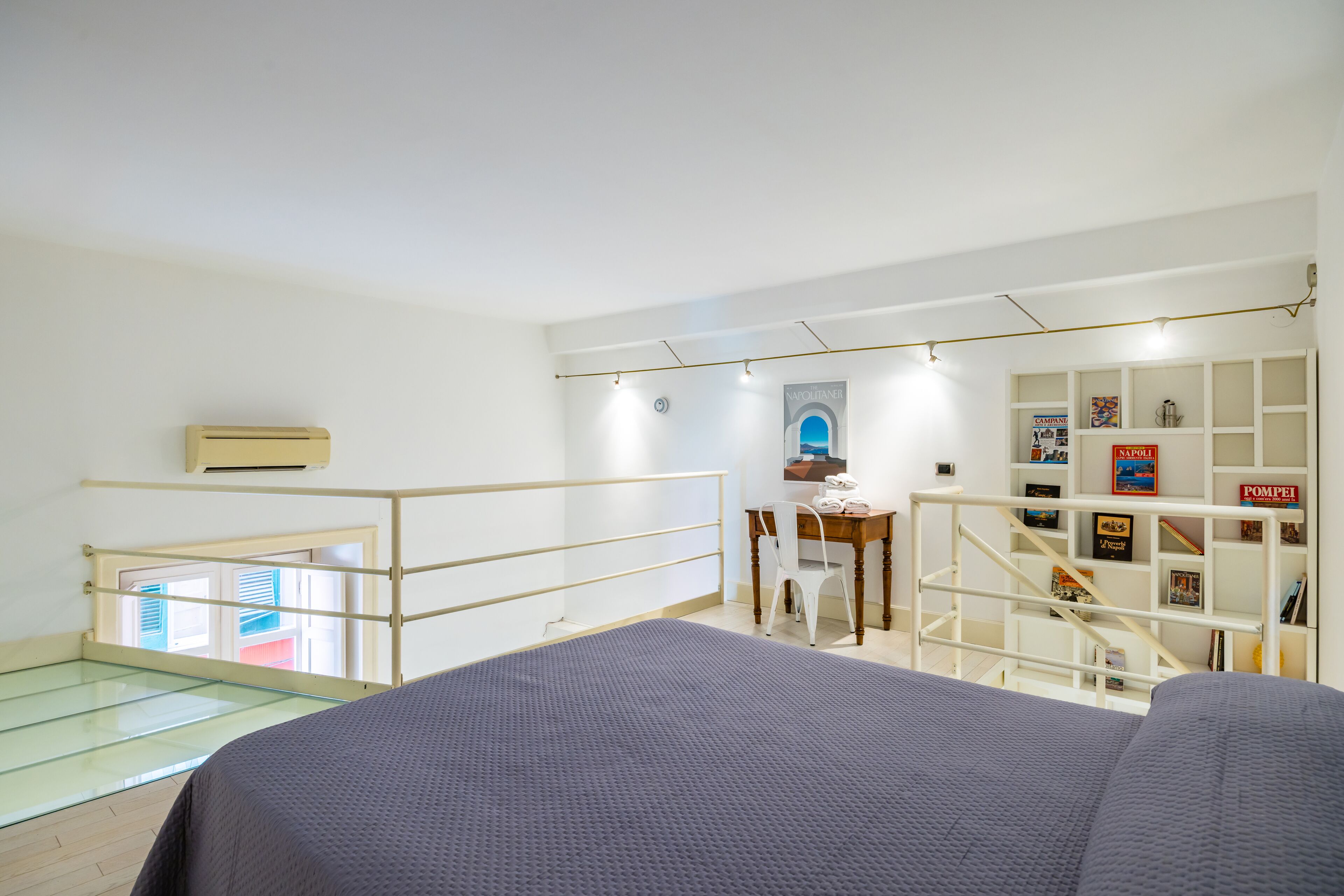 A modern bedroom with a bed, a desk, and a bookshelf.