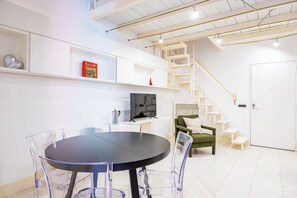 A modern living room with a round table, chairs, a television, and a staircase. - Chiaia Prestige by Napoliapartments (Naples)