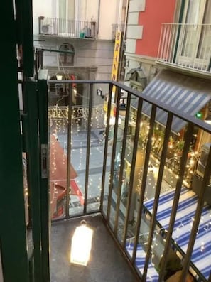 Ein Balkon mit Metallgeländer, Blick auf die Straße darunter und Lichterketten.