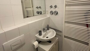 A bathroom with a white sink, mirror, and toilet.