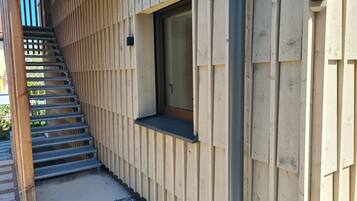Eine Holzfassade mit einer Metalltreppe, die zu einer Tür führt.