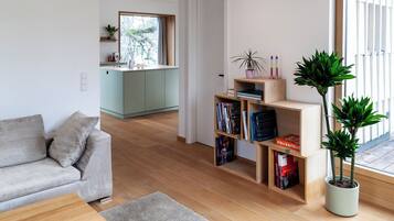 Ein modernes Wohnzimmer mit einer Couch, einem Couchtisch, einem Bücherregal und einer Topfpflanze.