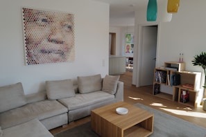 Una sala de estar moderna con un sofá, una mesa de centro y una obra de arte en la pared.