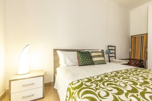A bedroom with a bed, bedside table, lamp, and a mirror. - Vacation Home Schiavone Family (Matera)