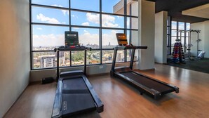 A gym with treadmills and a weight rack, large windows with a city view. - Elite Residence View Palace Apartment (Nairobi)