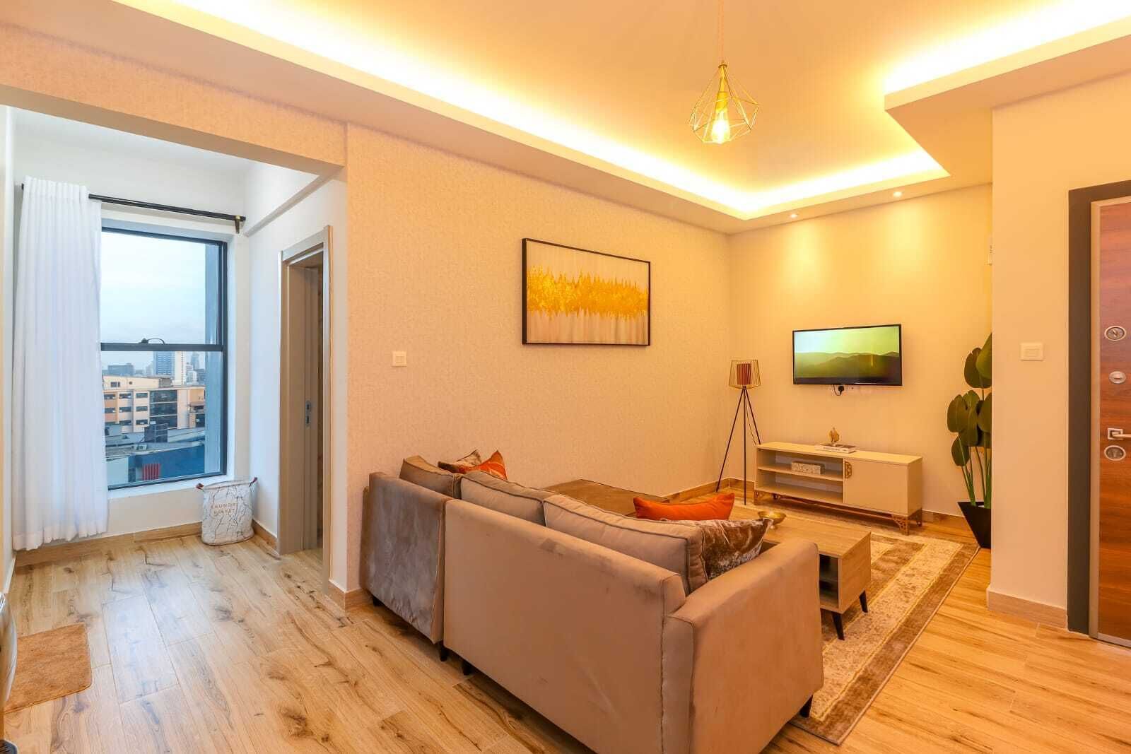Un salon moderne avec un canapé, un téléviseur et une lampe sur pied.
